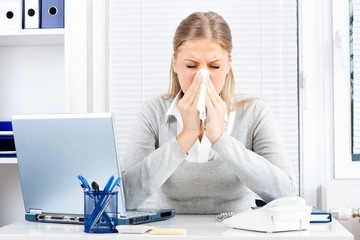 Frau mit Allergie und Heuschnupfen mit Taschentuch an der Nase